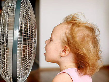 Girl cooling off in front of fan